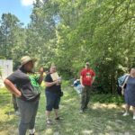 Group talking at farm while standing in shade.