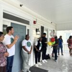 Person is speaking while group stands on porch. One person is holding balloons.