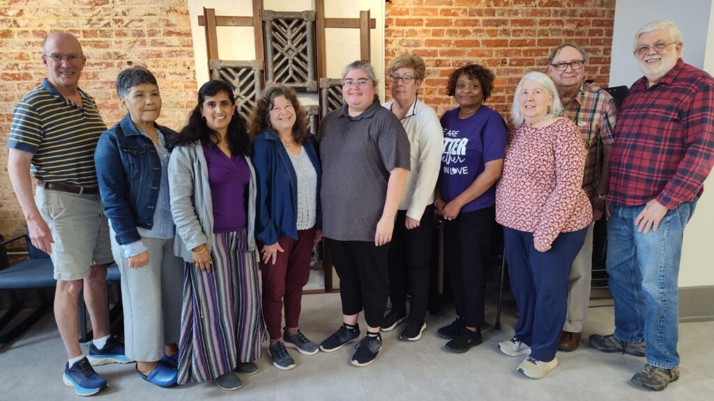 DCIA board. Group of 10 people stand in front of a mural.